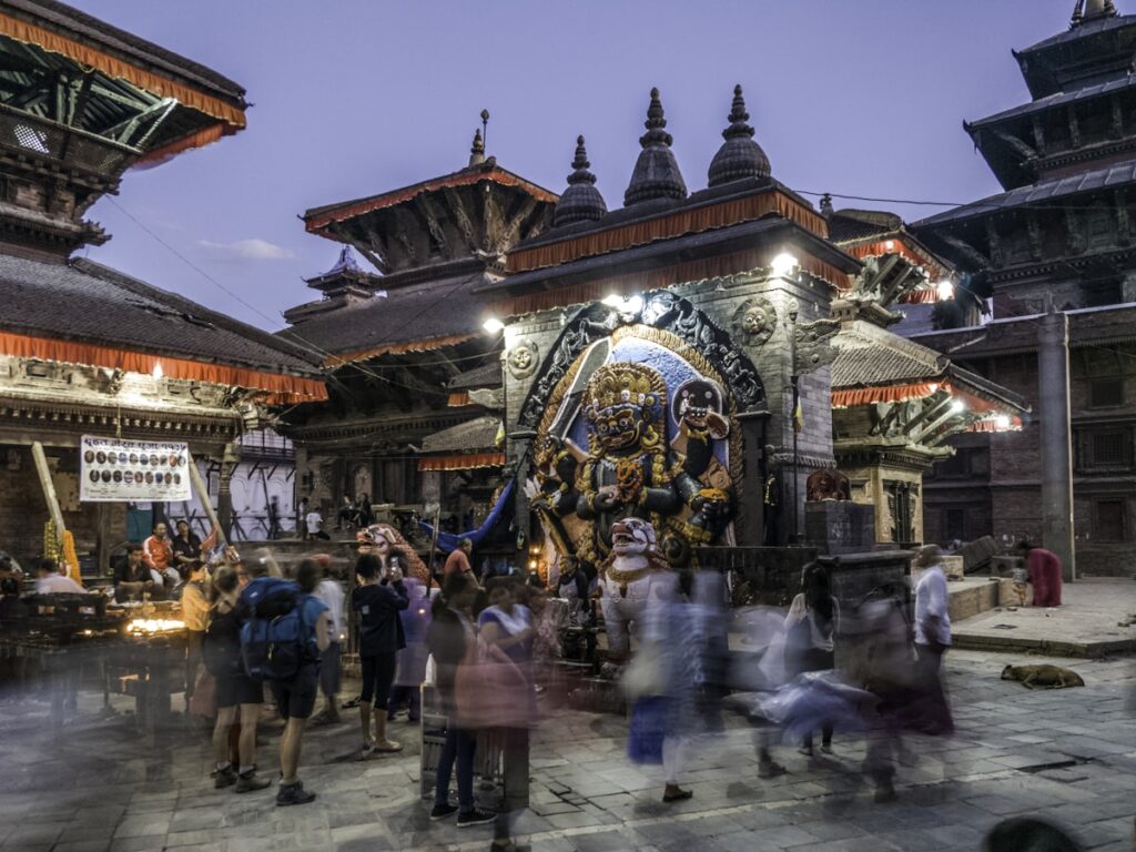 Pessoas em frente a estátua religiosa sob céu azul no Nepal